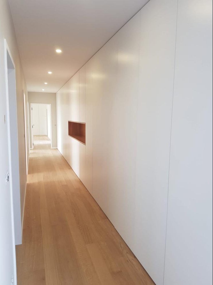 Corredor com roupeiro de parede branco e nicho em madeira